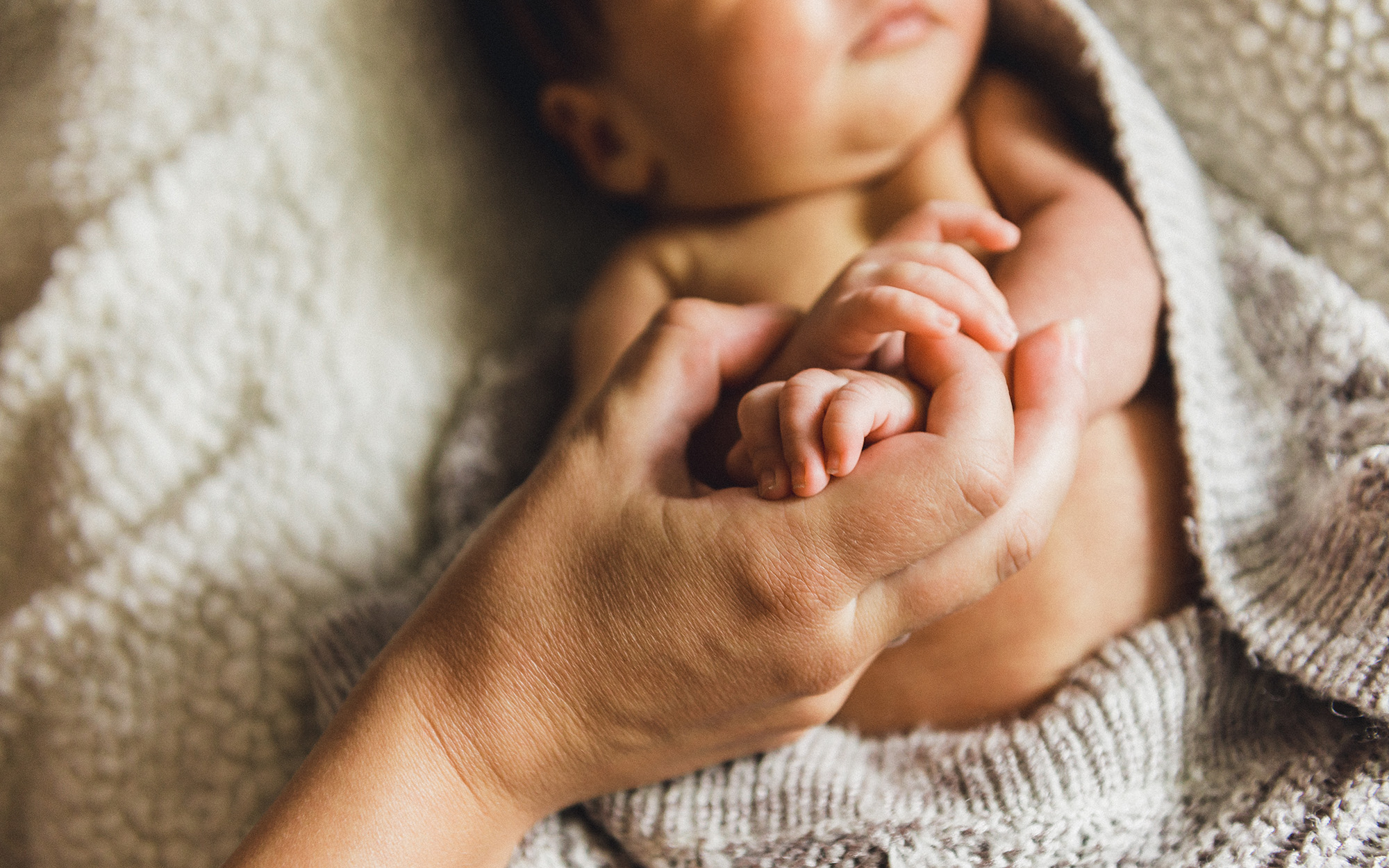 Mamma håller bebis händer